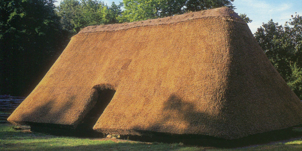 Reconstruction de la maison de Melrand : toit de chaume descendant presque jusqu’au sol