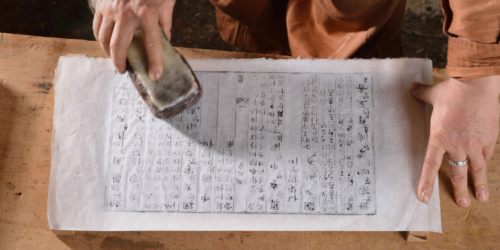 Impression d’une feuille par brossage manuel par Kim Gak-han, maître artisan spécialiste de la gravure sur bois