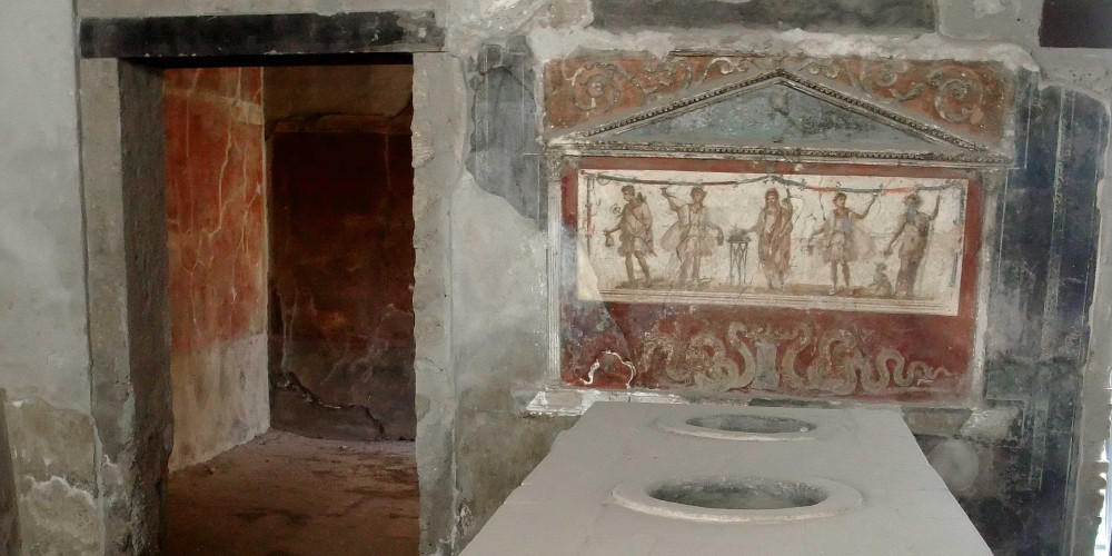 Comptoir d’un débit de boisson et autel des dieux lares (laraire) à Pompéi