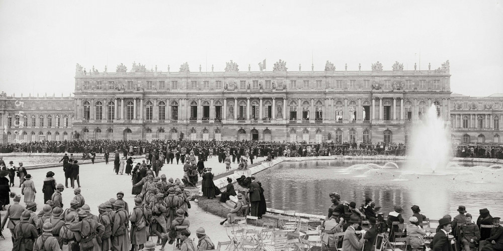 Foule autour des parterres d’eau du château de Versailles, présence de soldats français, le jour de la signature du traité de Versailles