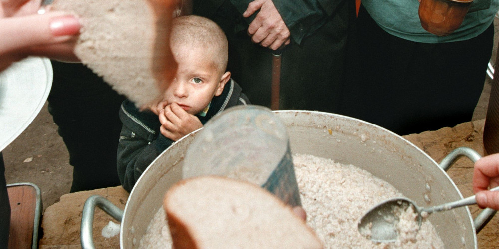 Un garçon attend son tour lors de la distribution d'une soupe populaire