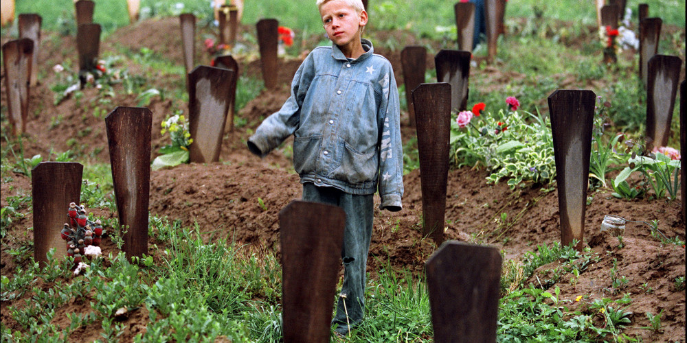 Un jeune garçon se tient au milieu des deux cents tombes du cimetière musulman de son village